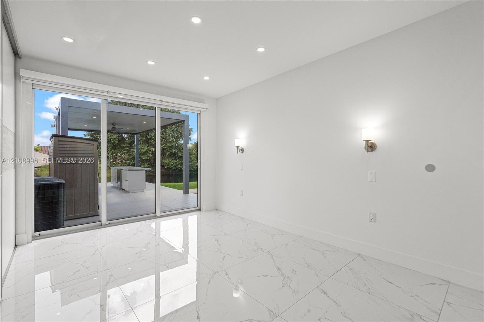 Large-format tile flooring with marble-style veining, recessed ceiling lighting, wall-mounted sconces, and sliding glass doors