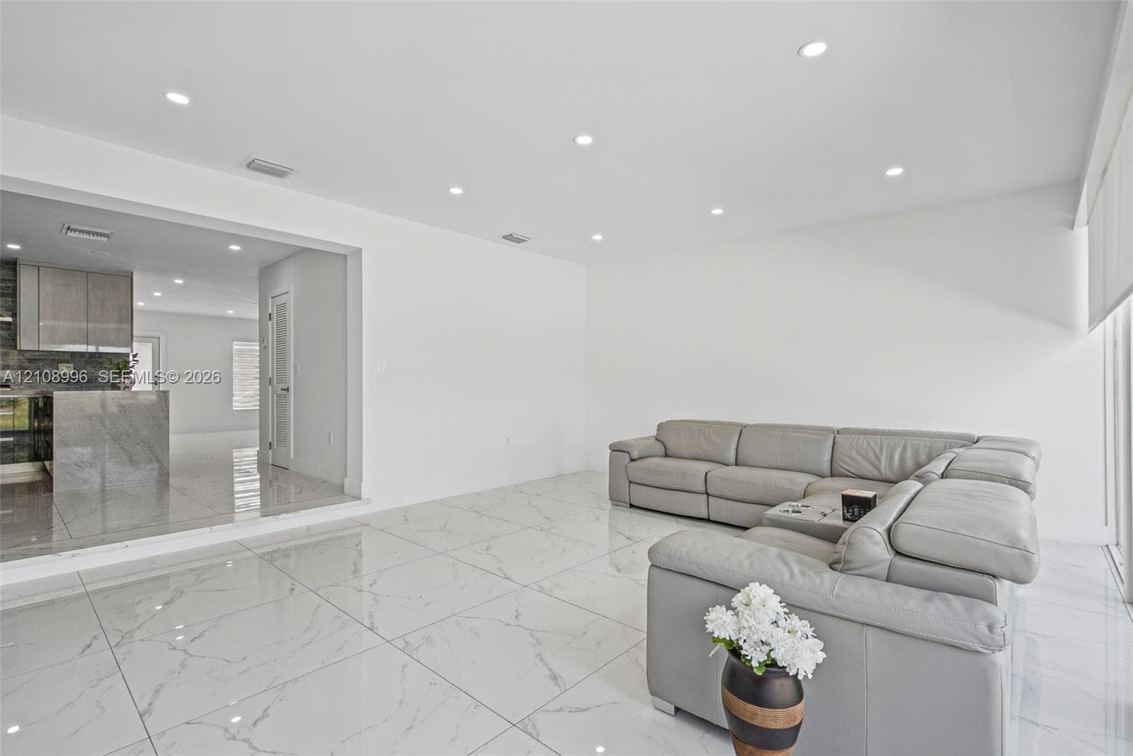 Large-format stone-patterned tile flooring, recessed ceiling lighting, and smooth-finish walls