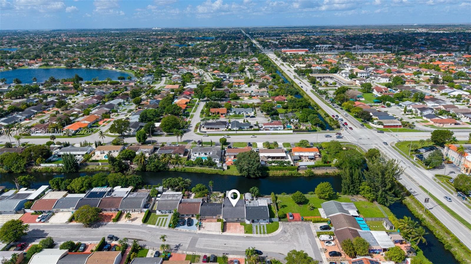 Aerial perspective of a single-story residence featuring a concrete tile roof, paved driveway, and canal-front positioning