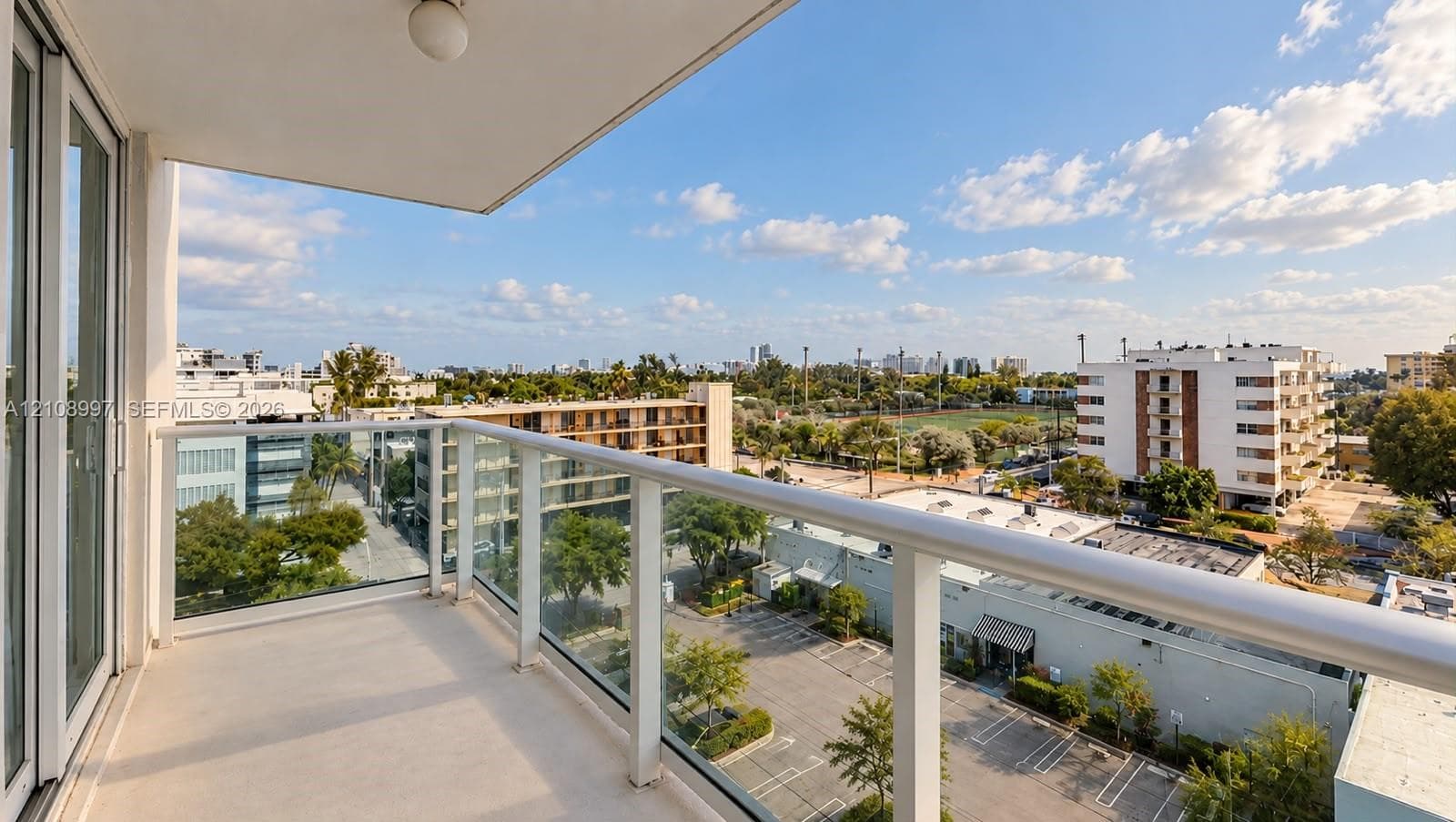 Private balcony featuring a glass-panel railing, concrete flooring, and an overhead flush-mount light fixture