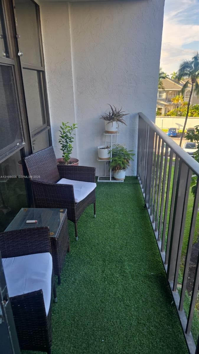 Covered balcony featuring artificial turf flooring, a metal railing, and textured wall finishes