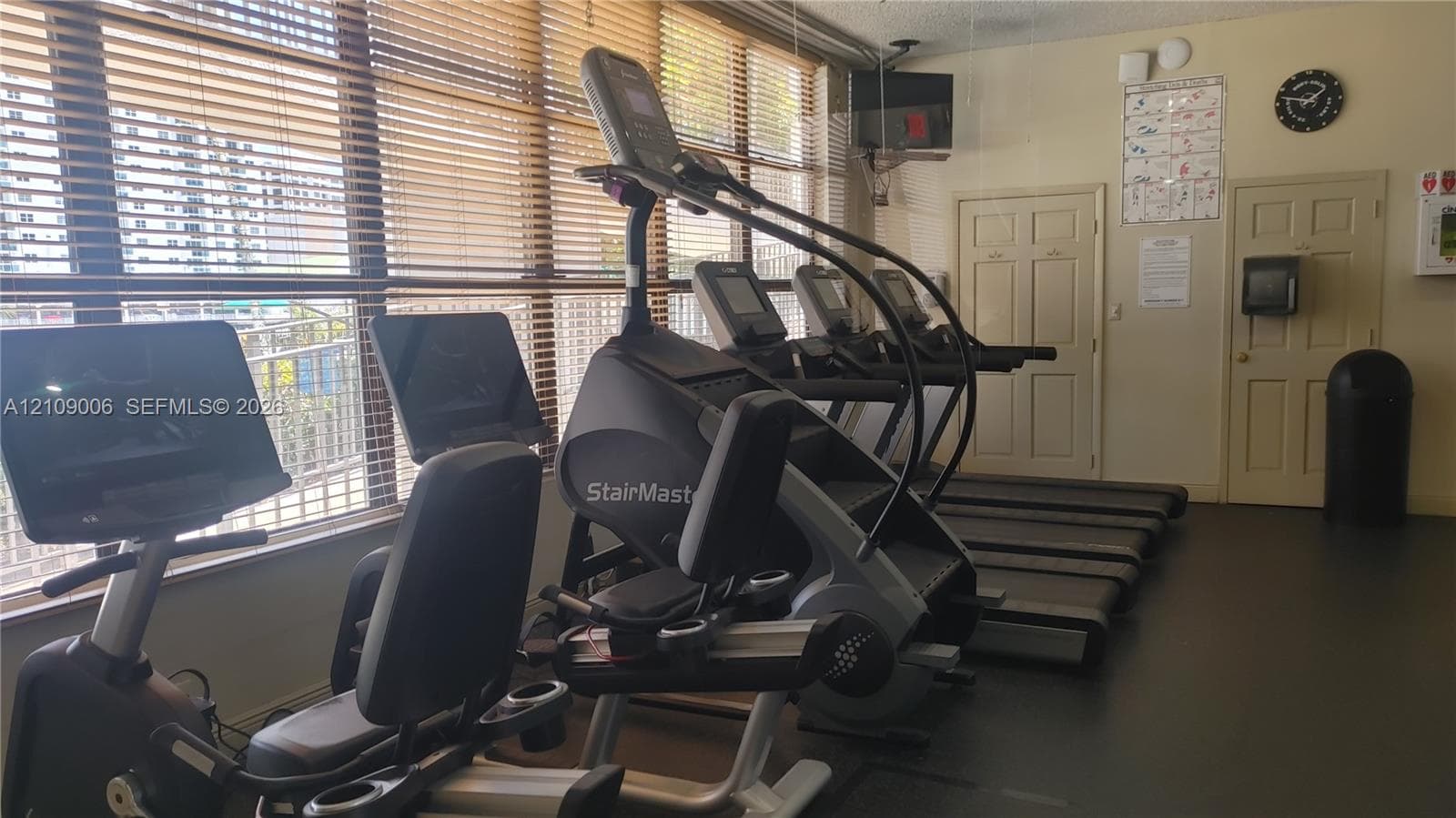 Fitness center featuring wall-to-wall windows with horizontal blinds and resilient flooring