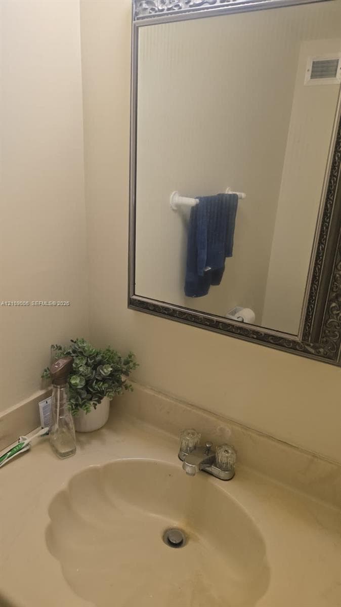 Wall-mounted mirror with decorative metallic frame, integrated countertop sink, and dual-knob faucet