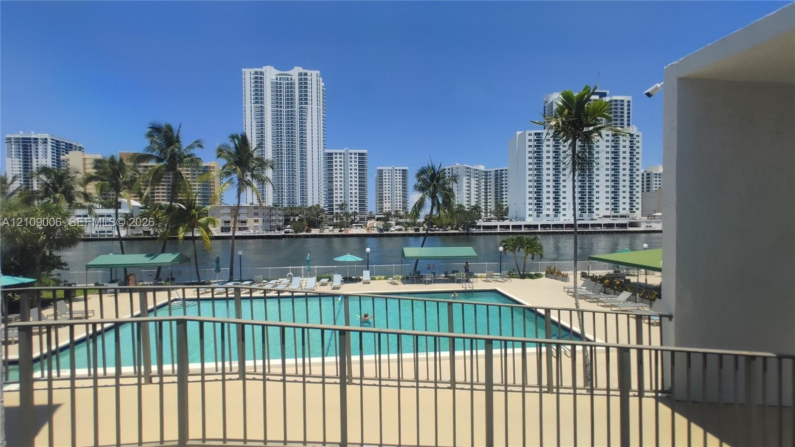 Waterfront swimming pool with a concrete deck, metal railings, and natural surroundings