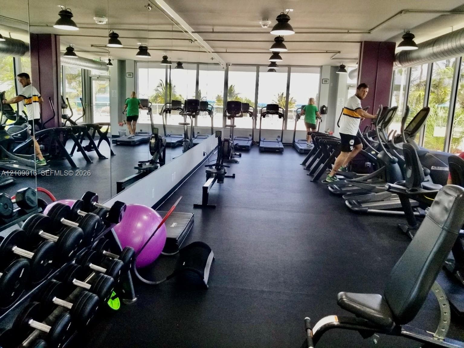 Fitness center featuring rubber flooring, expansive floor-to-ceiling windows, and wall-to-wall mirrors