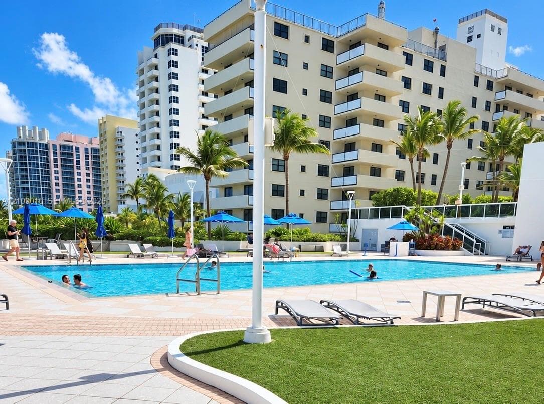 Swimming pool with paver decking, manicured lawn, and mature palm trees