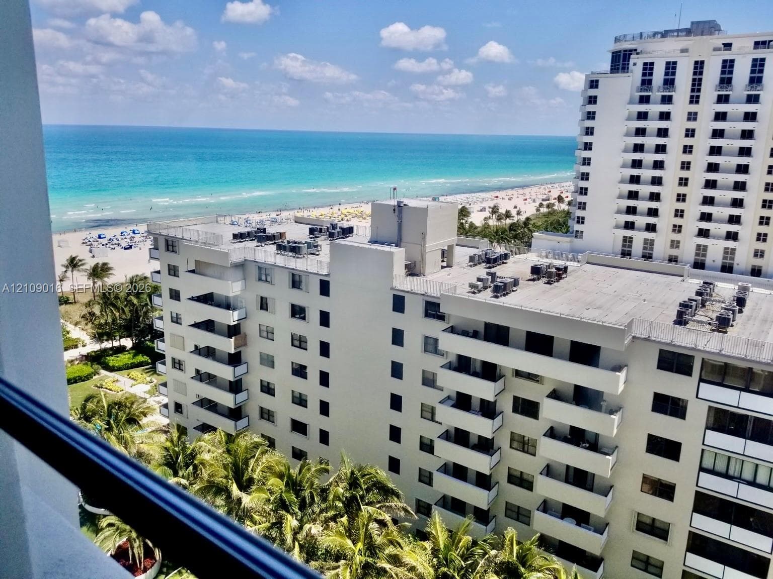 Elevated outdoor balcony featuring a metal railing with a direct ocean and beach vista