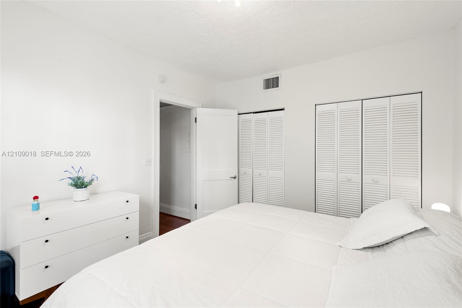 Neutral interior space featuring white walls, white louvered-style closet doors, and a solid-core interior door