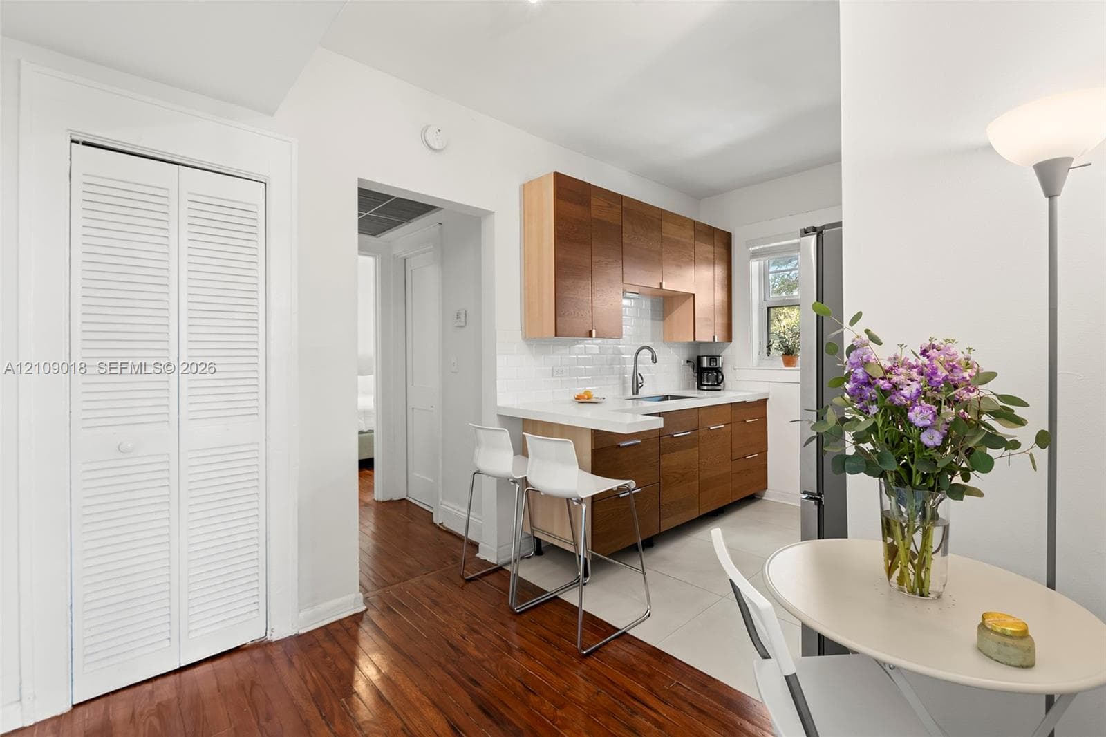 Kitchen featuring wood-finish cabinetry, white solid-surface countertops, a subway tile backsplash, and wood-finish flooring