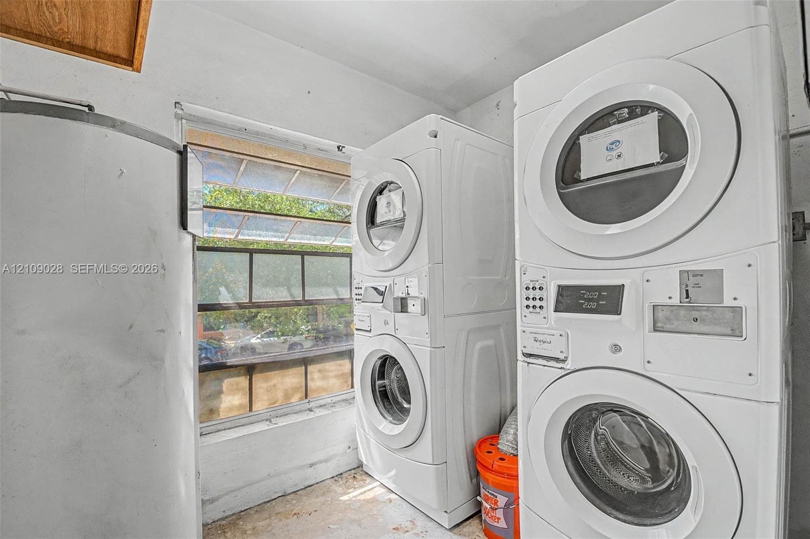 Laundry area featuring two stacked washer and dryer units and a multi-pane horizontal window