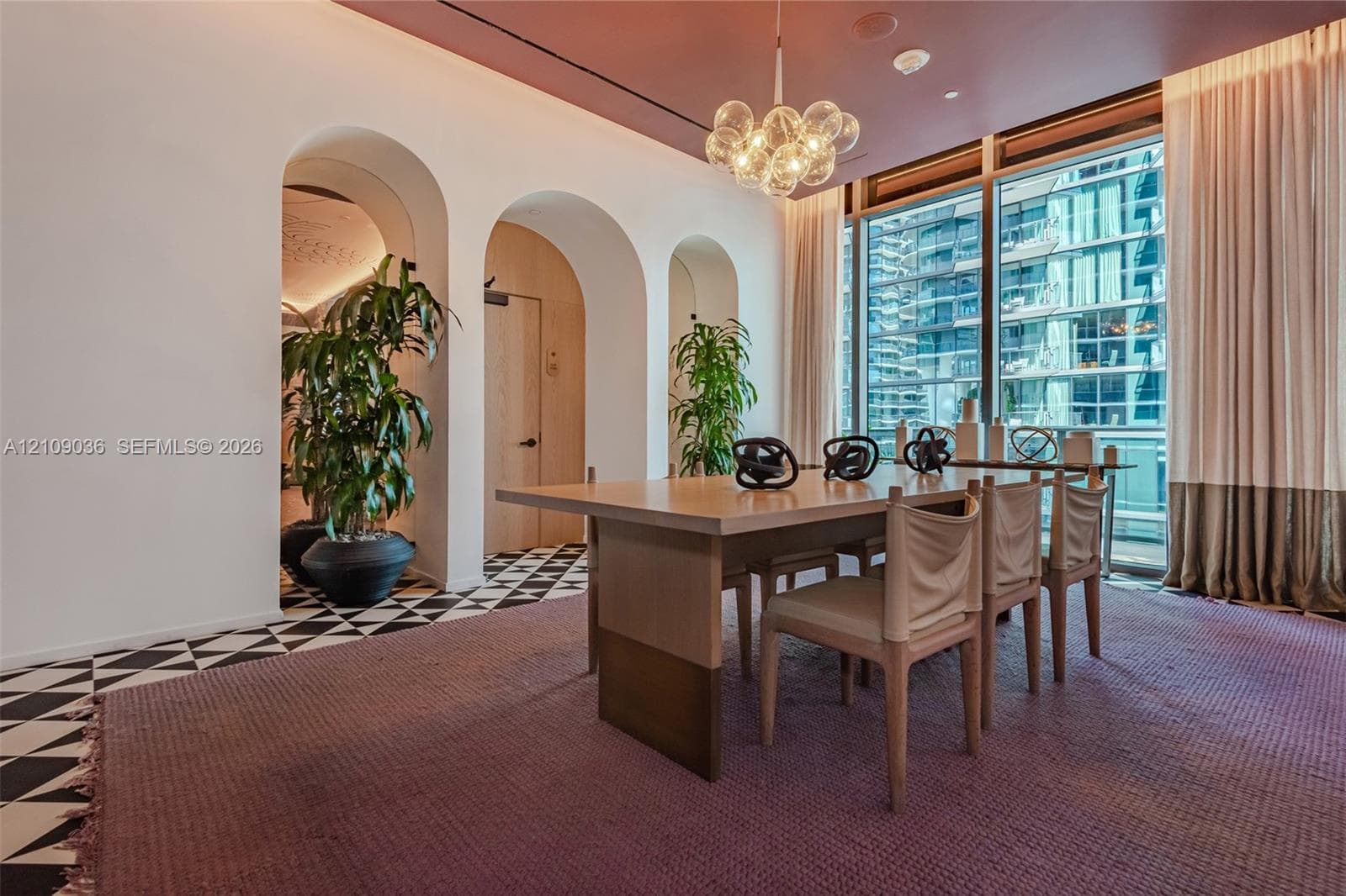 Architectural arched entryways, floor-to-ceiling windows with full-height drapery, geometric pattern tile flooring, and a multi-globe glass pendant light fixture
