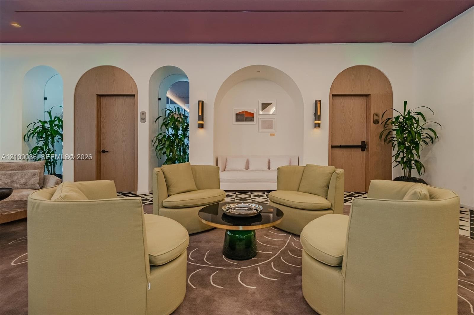 Interior space featuring rhythmic arched wood-framed doorways, recessed wall niches, wall-mounted light fixtures, and high-contrast geometric floor tiling