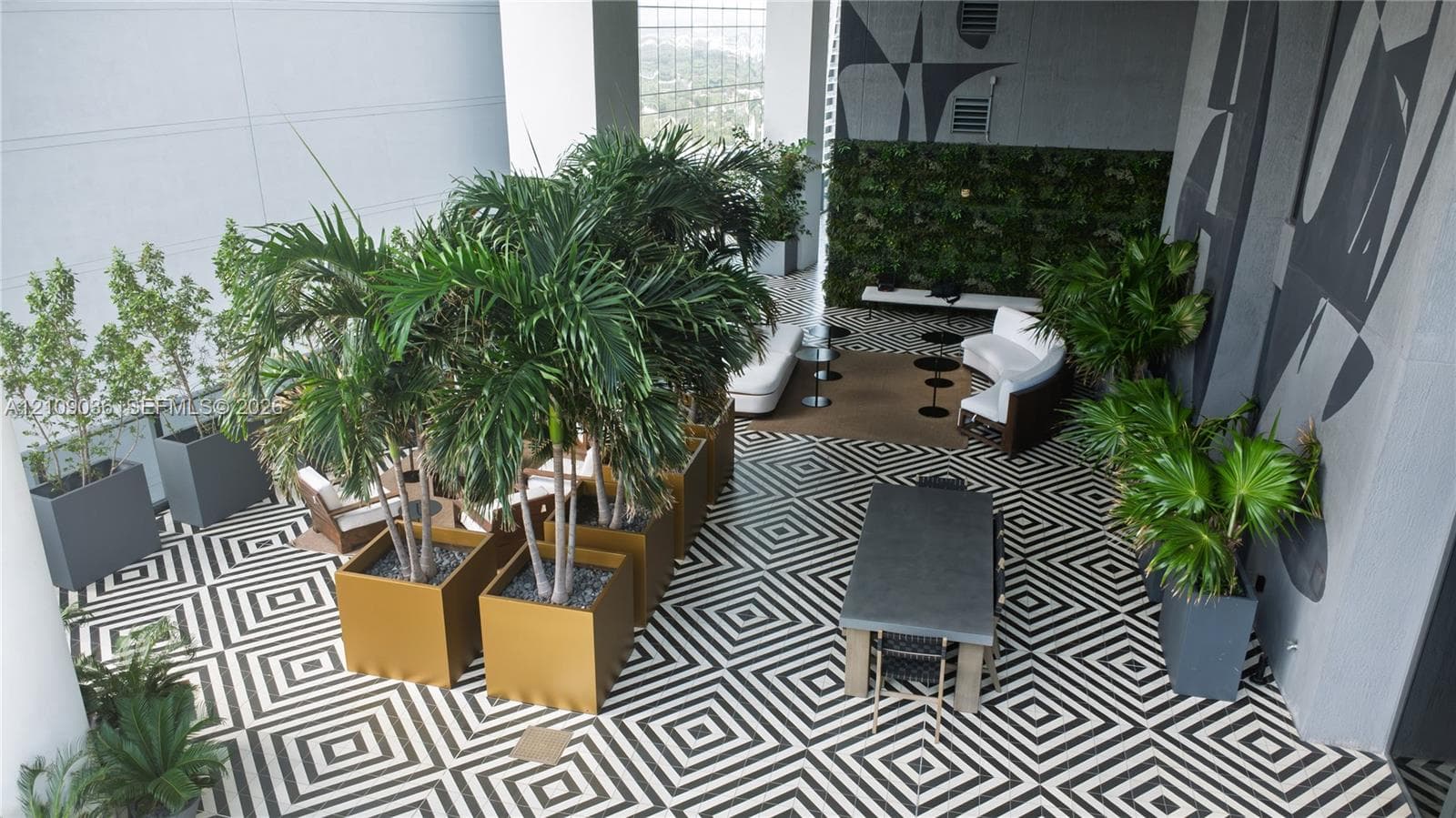 Covered terrace featuring geometric patterned floor tiling, built-in vertical green wall, and large-scale architectural planters