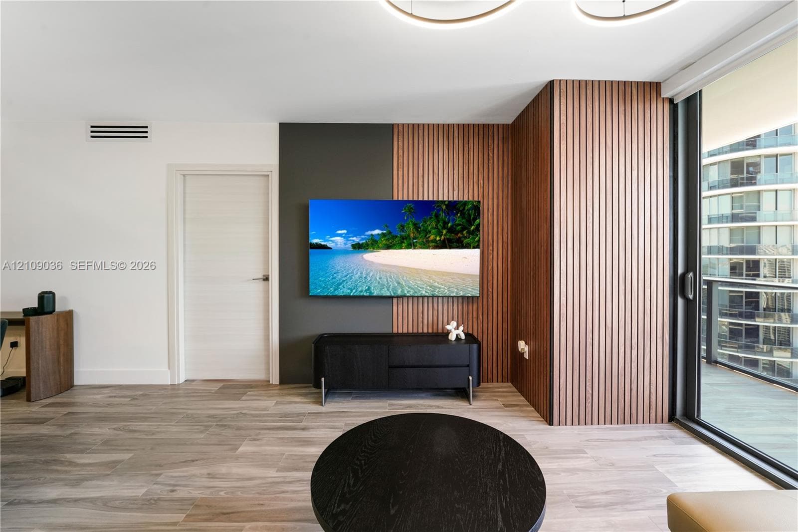 Interior featuring wood-finish flooring, floor-to-ceiling slatted wood wall paneling, and an expansive sliding glass door system