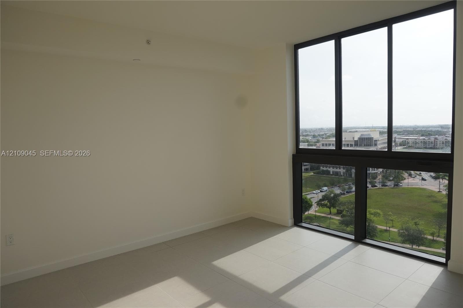 Floor-to-ceiling windows with black frames, tile flooring, and neutral wall tones