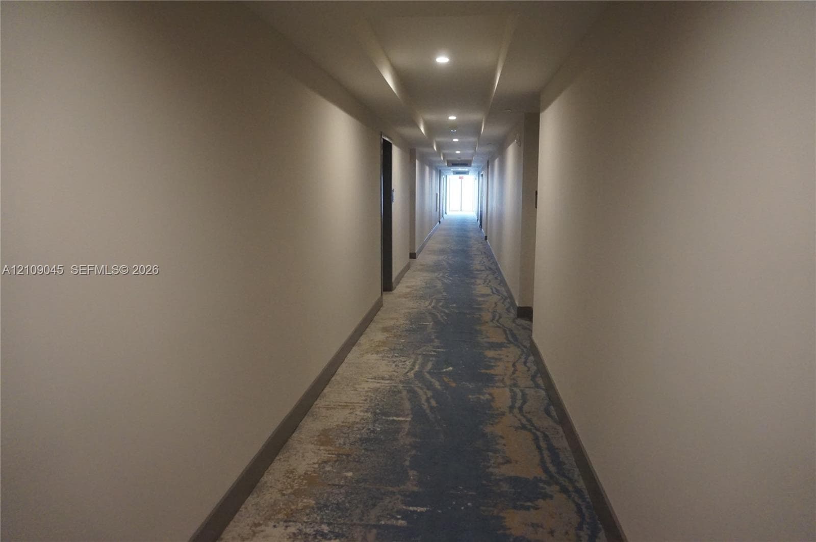 Hallway featuring patterned carpet flooring, recessed ceiling lighting, and neutral-toned walls