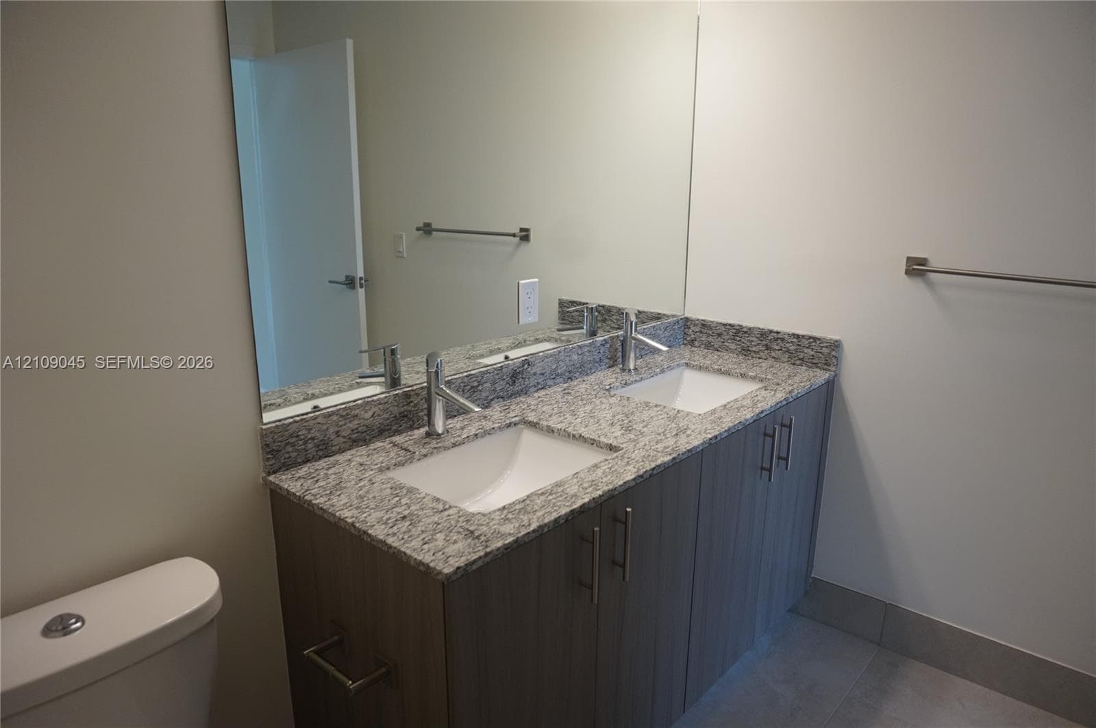 Dual-sink vanity with stone-finish countertop, undermount sinks, tall chrome faucets, and wood-finish cabinetry