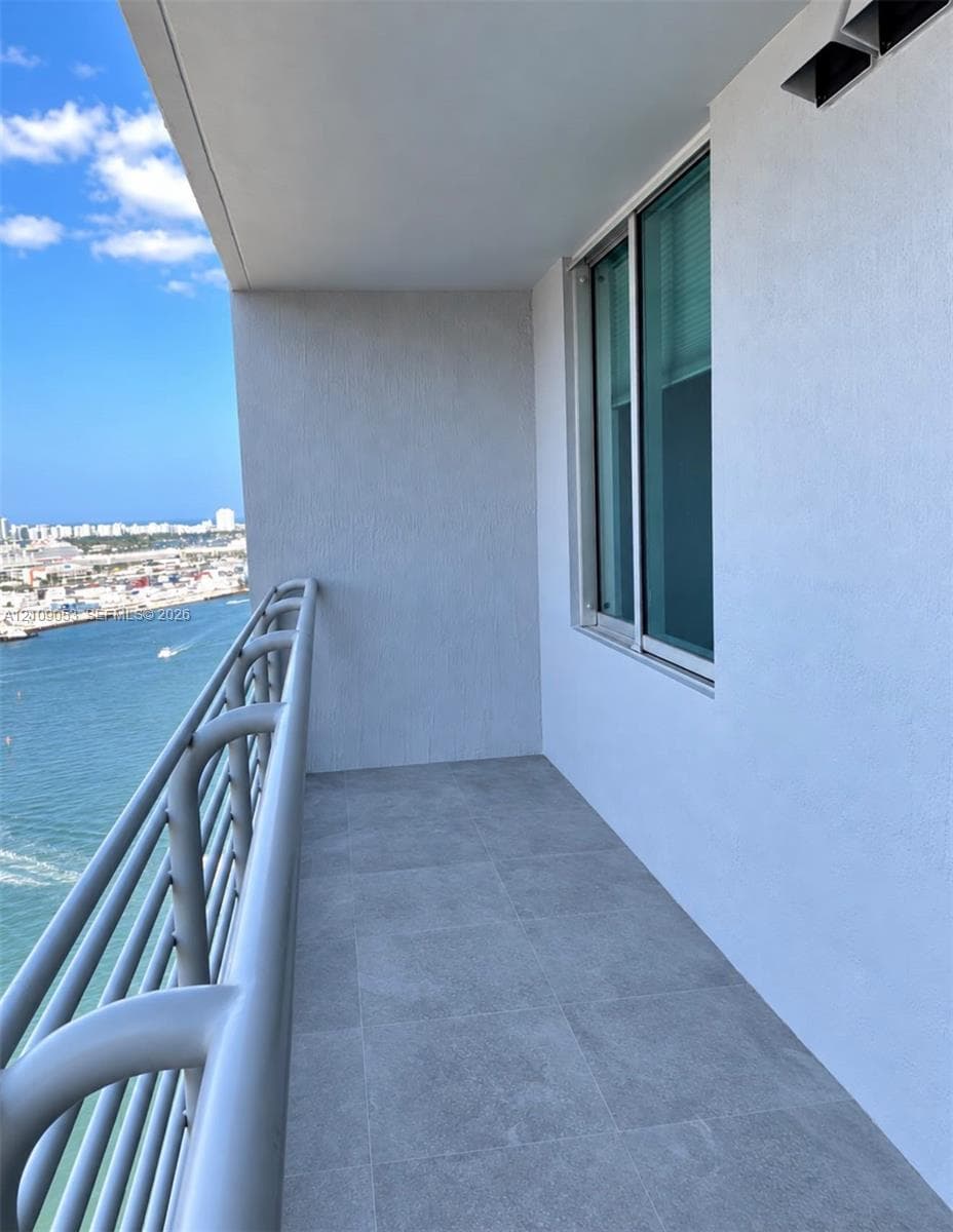 Private balcony featuring large-format tile flooring, metal tubular railings, and expansive water frontage