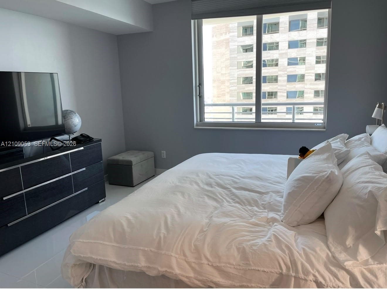 Neutral-toned room featuring large floor-to-ceiling windows, polished tile flooring, and integrated solar shade