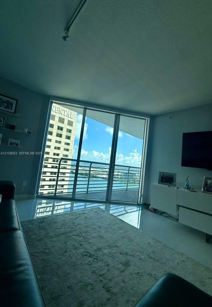 Floor-to-ceiling glass paneling, balcony with metal railing, and high-gloss tile flooring