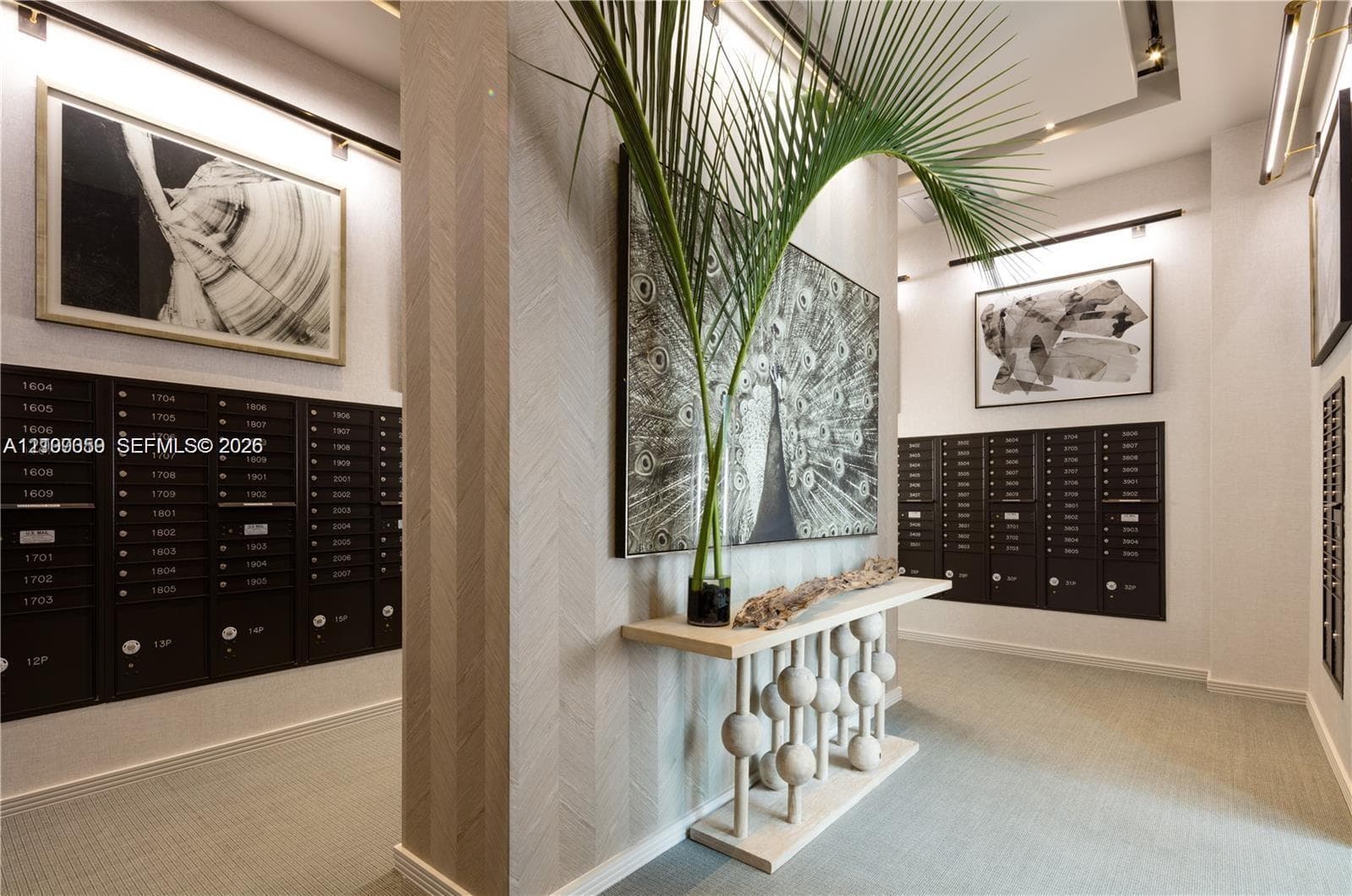 Mail room area featuring dark metallic parcel lockers, textured herringbone wall surfaces, track lighting, and a neutral color palette