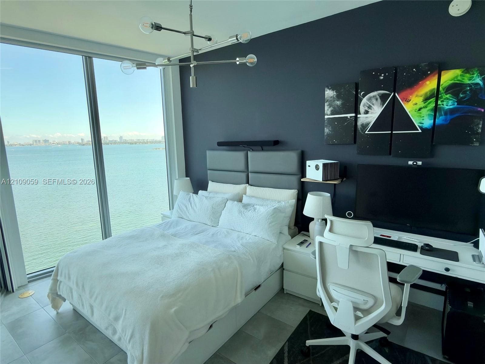 Floor-to-ceiling windows, porcelain tile flooring, modern metal multi-arm chandelier, and accent wall