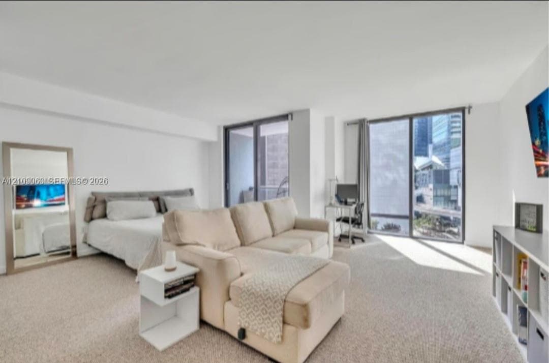 Floor-to-ceiling glass sliding doors, neutral carpeting, and urban exterior backdrop