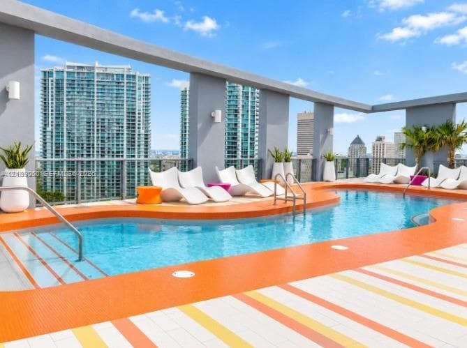 Rooftop swimming pool with integrated stair entry, overhead architectural structural beams, and textured perimeter surfacing