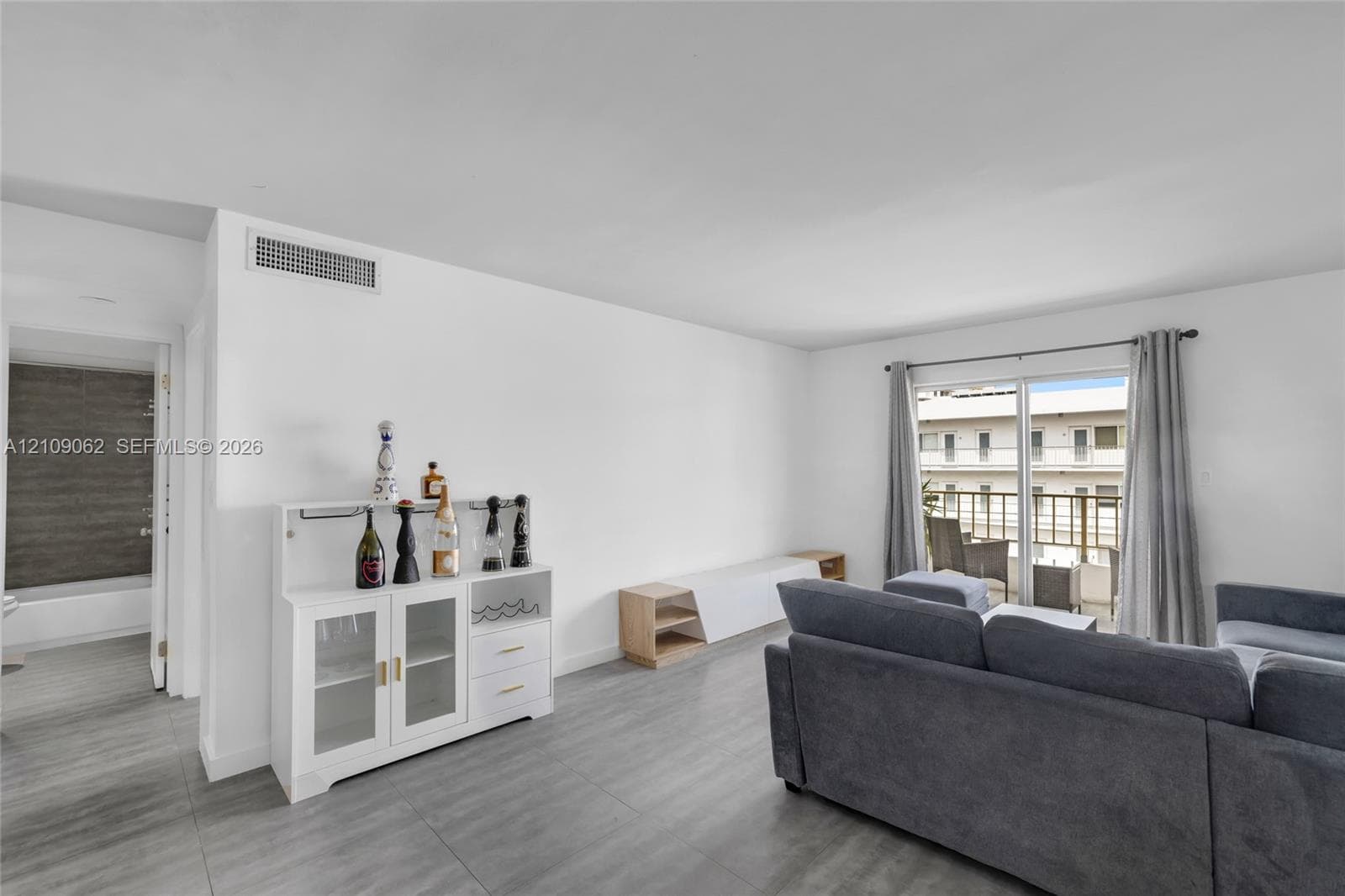 Open-concept interior featuring large-format tile flooring and a sliding glass door providing external access