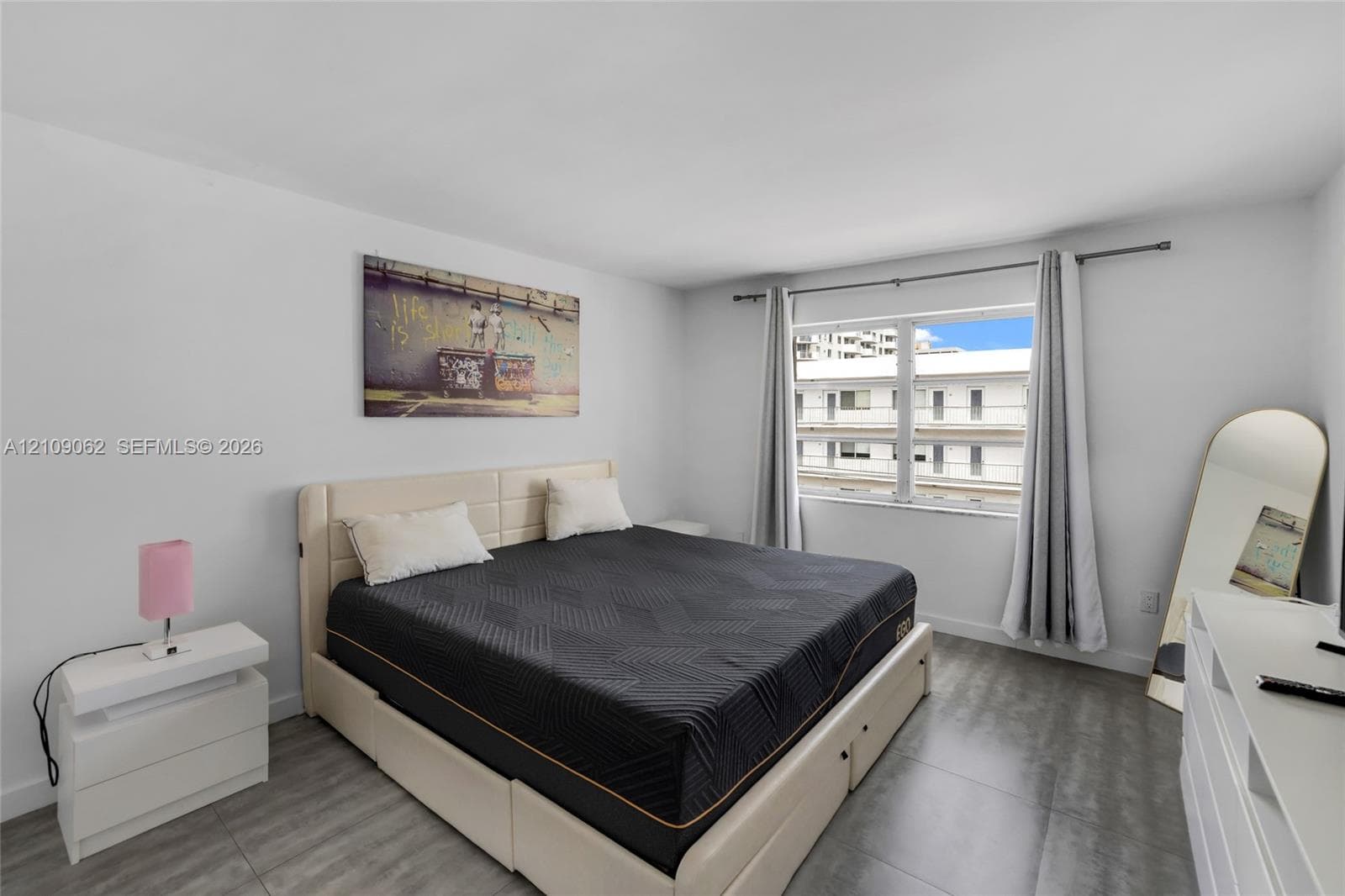 Neutral interior space featuring smooth wall finishes, large-format tile flooring, and a single-pane window with adjustable hardware