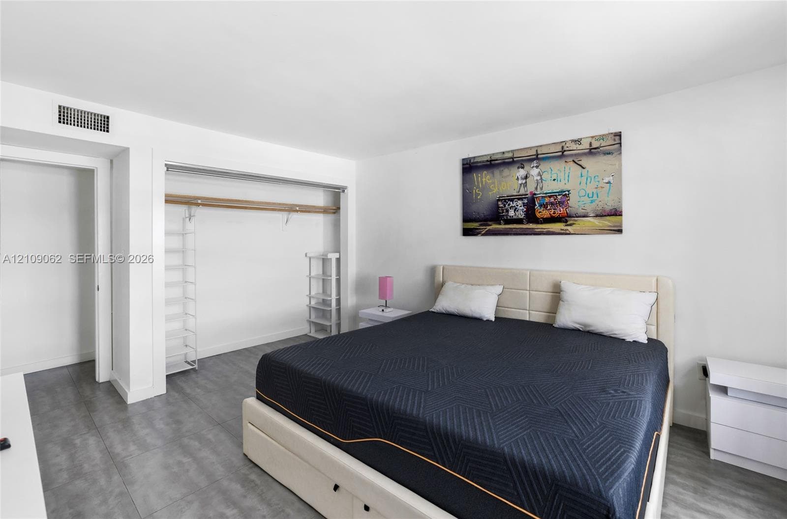 Room featuring grey tile flooring, white walls, and a recessed closet with a horizontal rod