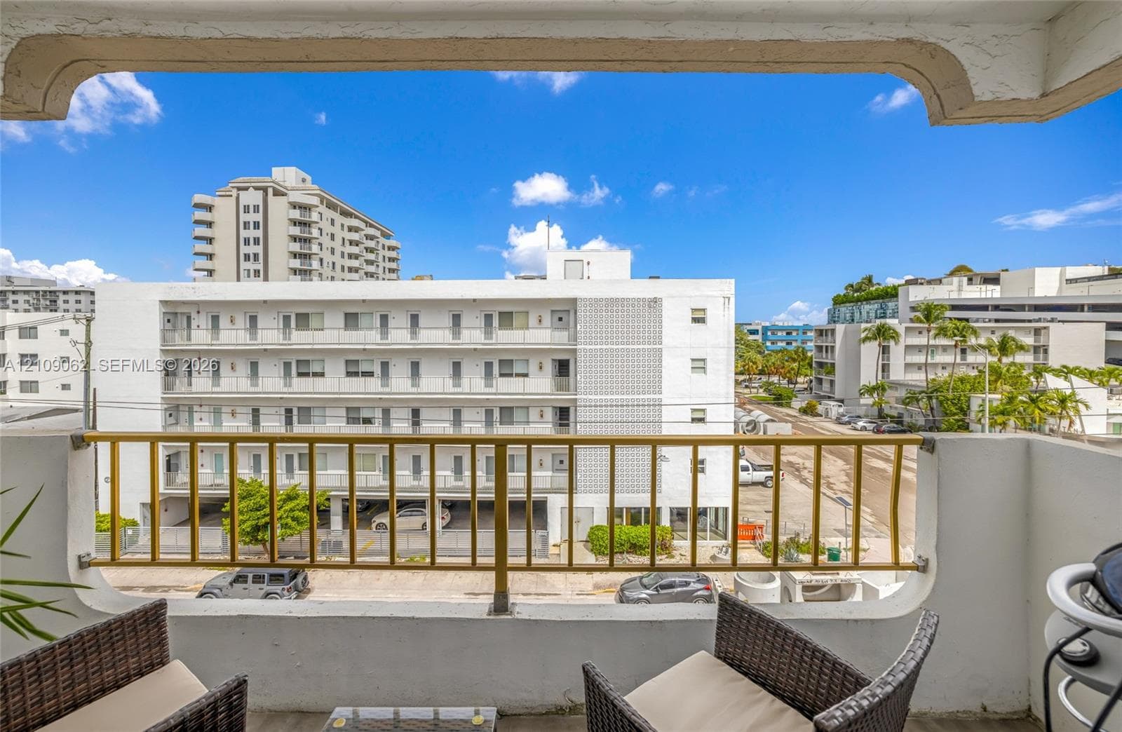 Covered balcony featuring a concrete floor, stucco-finish surround, and decorative arched framing with metal railings
