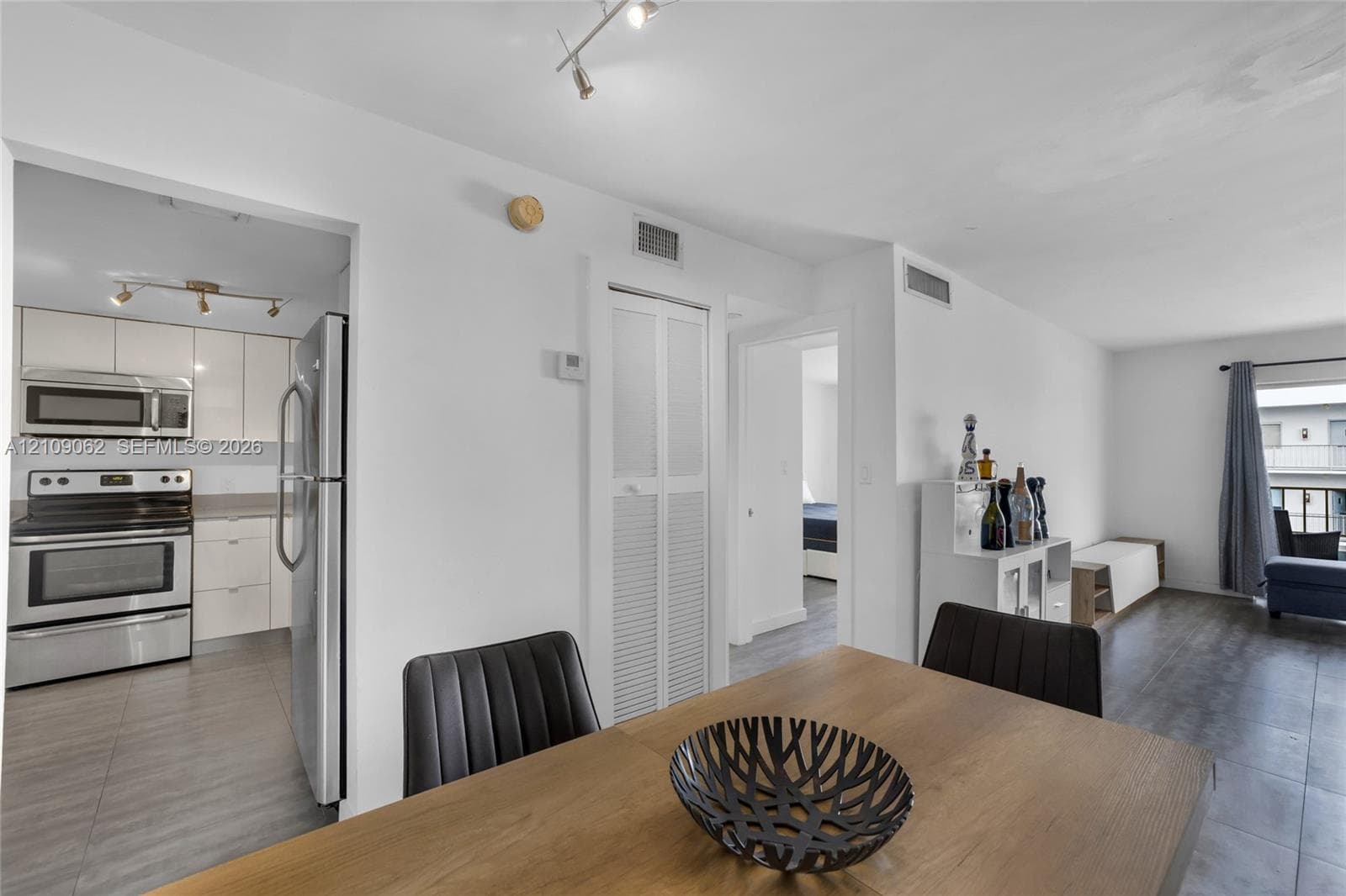 Kitchen area featuring high-gloss cabinetry, stainless steel appliances, wood-finish flooring, and track lighting