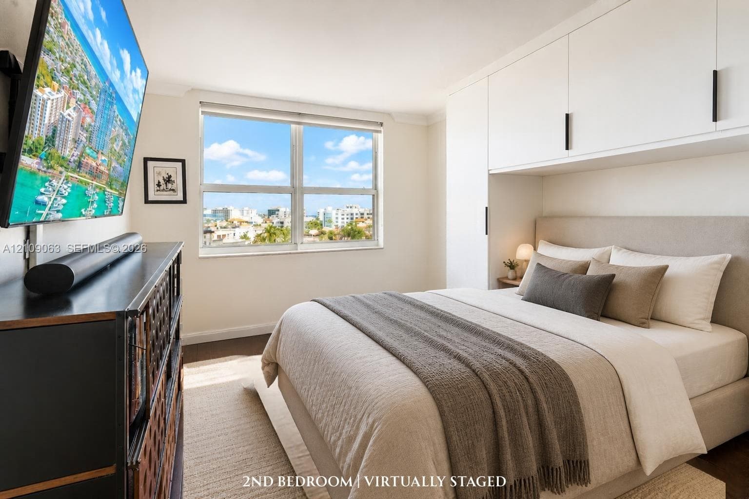 Built-in white overhead cabinetry with matte black hardware and a large window featuring an urban and water-side backdrop