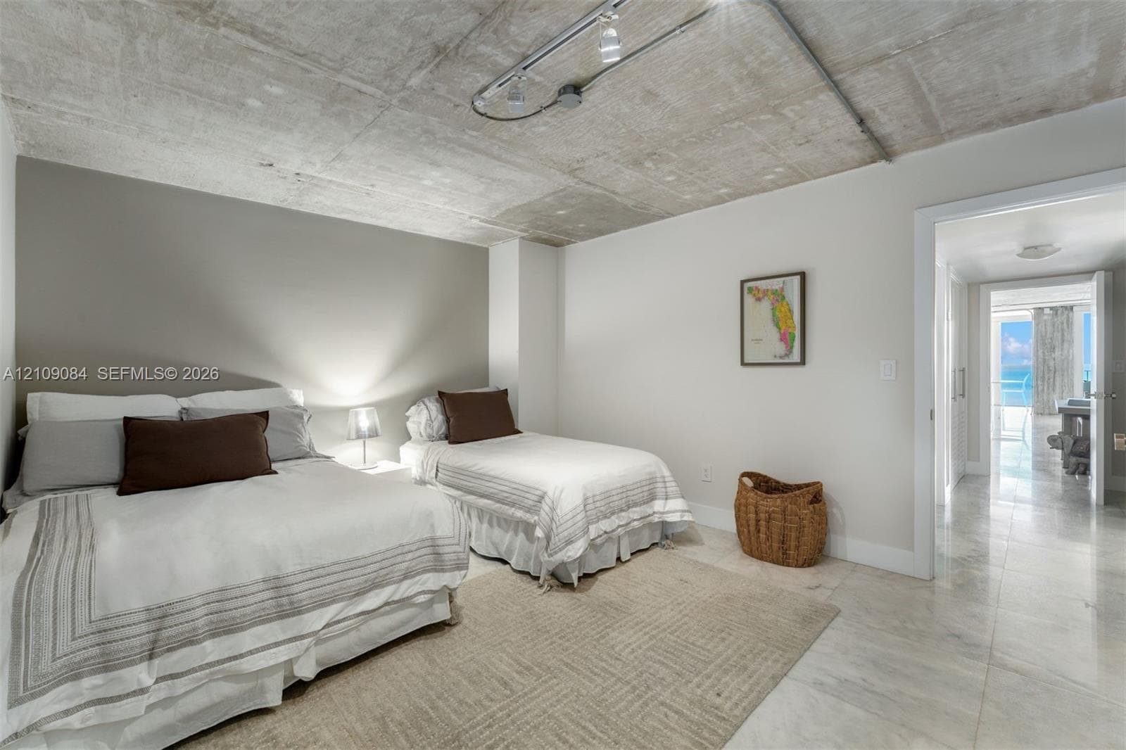 Exposed concrete ceiling with industrial-style track lighting, large-format tile flooring, and custom wall-mounted wood cabinetry with integrated shelving