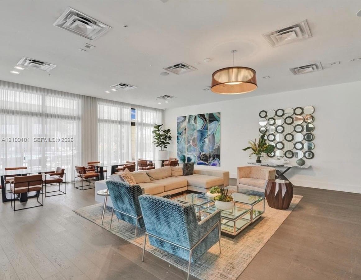Expansive interior featuring floor-to-ceiling windows, wood-finish flooring, recessed ceiling lighting, and a circular drum pendant light fixture