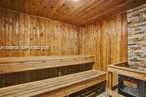 Sauna featuring wood-plank walls and ceiling, multi-level built-in wood benches, and a stone-accented heating unit