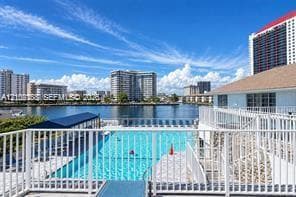 Swimming pool with white metal perimeter fencing, elevated balcony, and water frontage