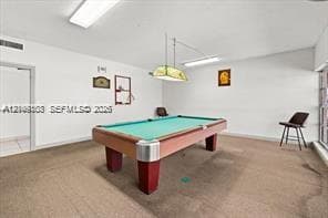 Interior space featuring neutral-toned carpeting, rectangular recessed overhead lighting, and a hanging geometric light fixture