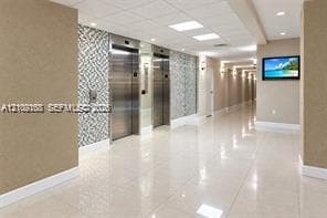 Elevator lobby featuring polished tile flooring, stainless steel elevator doors, recessed ceiling lighting, and decorative wall paneling