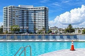 Swimming pool with metal handrail, concrete pool deck, and perimeter fencing