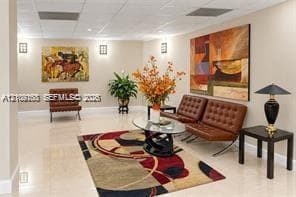Common area featuring high-gloss tile flooring, drop ceiling panels, and wall-mounted sconce lighting