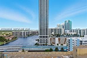 High-rise tower featuring a glass facade, situated along a waterfront canal