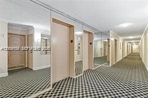 Hallway featuring wall-to-wall mirrored panels, patterned carpeting, and recessed ceiling lighting