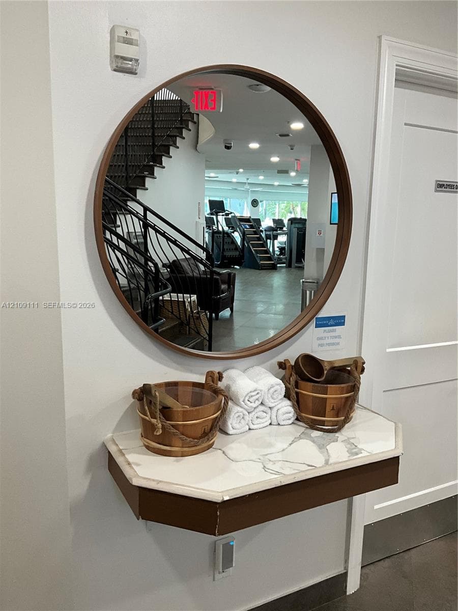 Wall-mounted floating vanity featuring a stone-look countertop and a circular mirror with a wood-finish frame