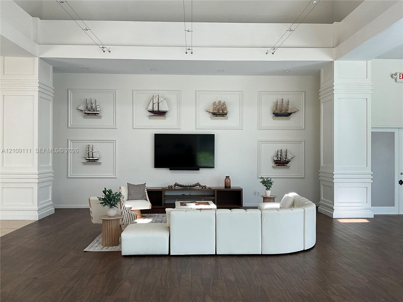 Tray ceiling with recessed lighting, prominent architectural columns with millwork, and dark wood-finish flooring