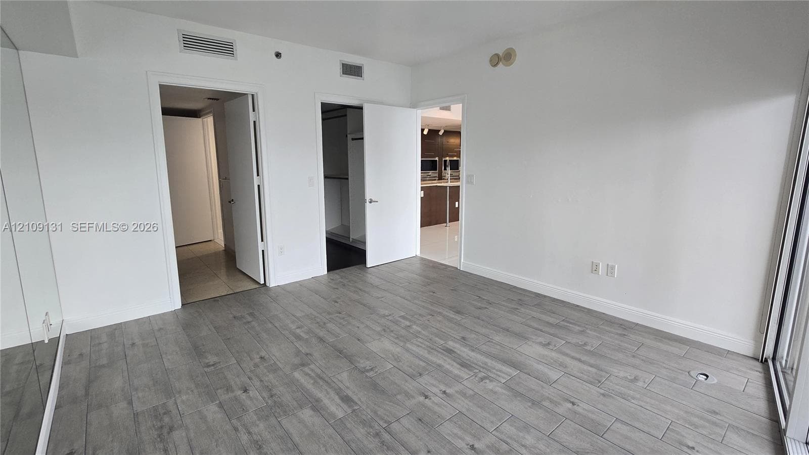 Wood-finish flooring throughout, mirrored wall paneling, and multiple interior doorways with white slab doors