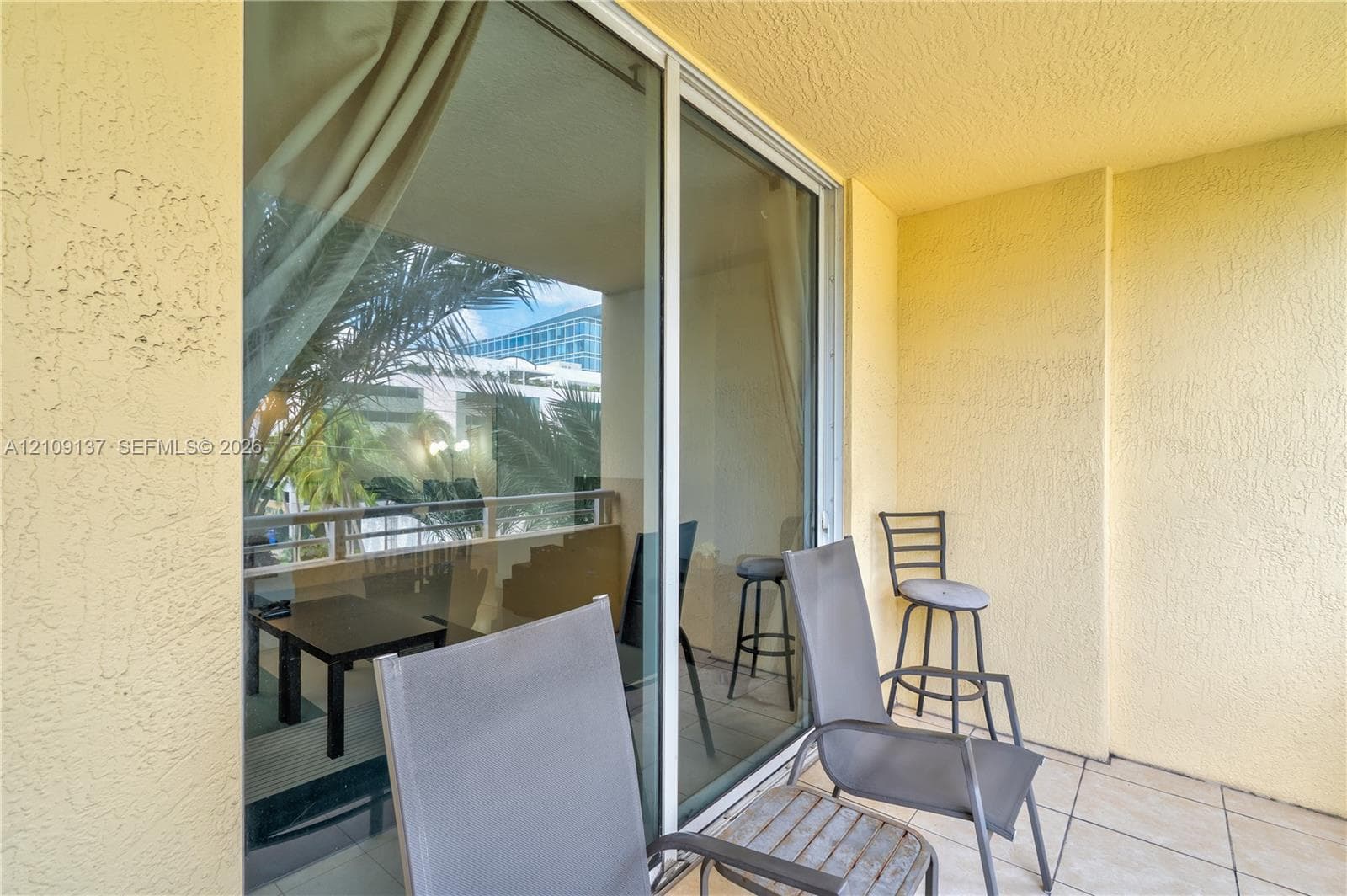 Private balcony with tile flooring, stucco wall finish, and sliding glass door entry
