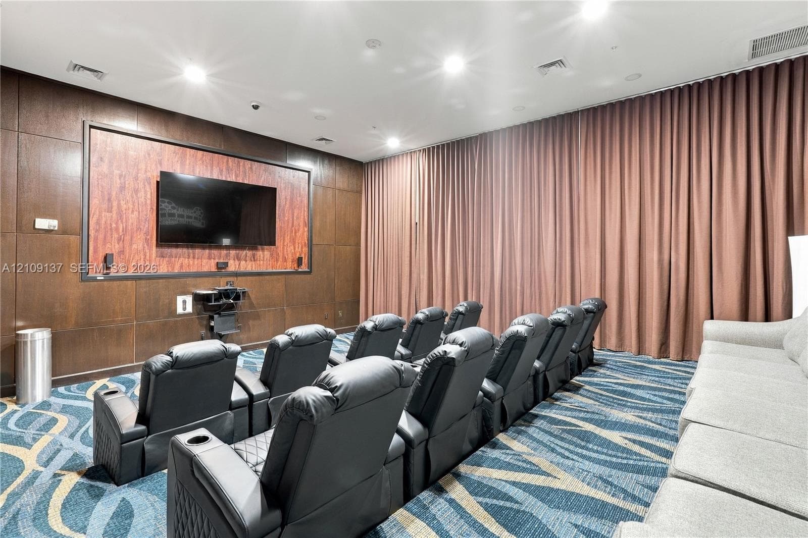 Media room featuring wood-paneled walls, full-height wall drapery, and integrated recessed lighting