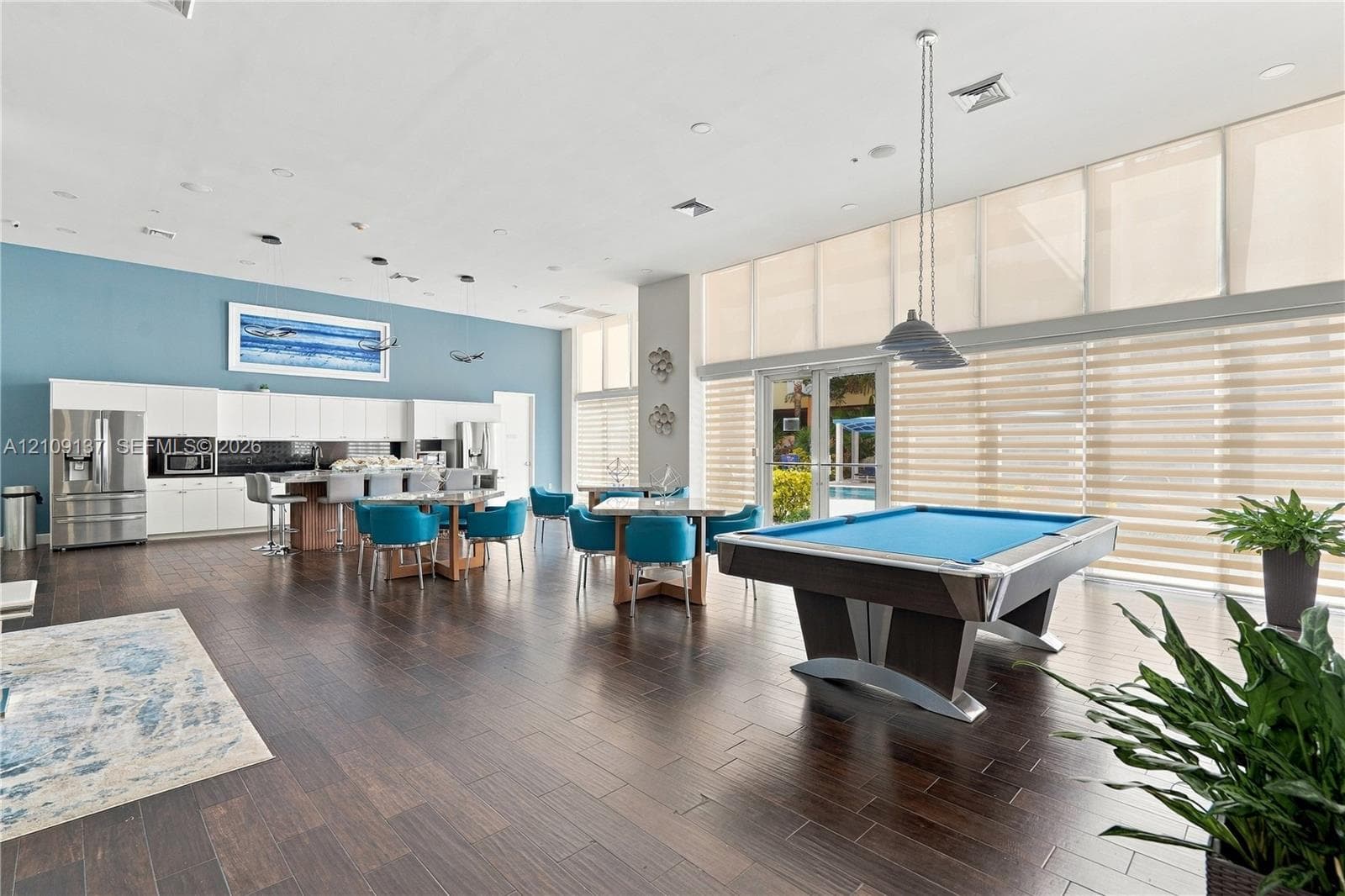 Open-concept room featuring wood-finish flooring, floor-to-ceiling windows, built-in cabinetry, recessed lighting, and suspended multi-light fixtures